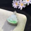 Close-up detail of carved icy green Buddha on jadeite pendant with 18K gold frame