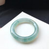 Side angle showing the bangle’s green swirls and glossy surface