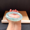 Woman wearing jade bangle bracelet on wrist in natural light