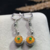 Front view of 18K gold orange-yellow jade dangling earrings with smooth circular peace buckle design