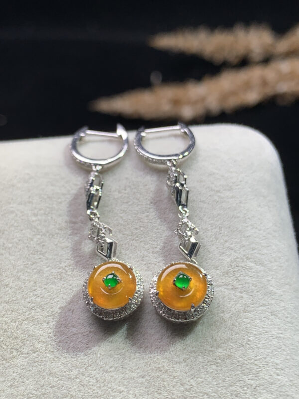 Front view of 18K gold orange-yellow jade dangling earrings with smooth circular peace buckle design