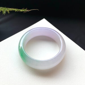 Spring-tinted wide-band jade stone bracelet symbolizing peace and prosperity.