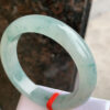 Close-up of floating floral inclusions in icy green jade bangle