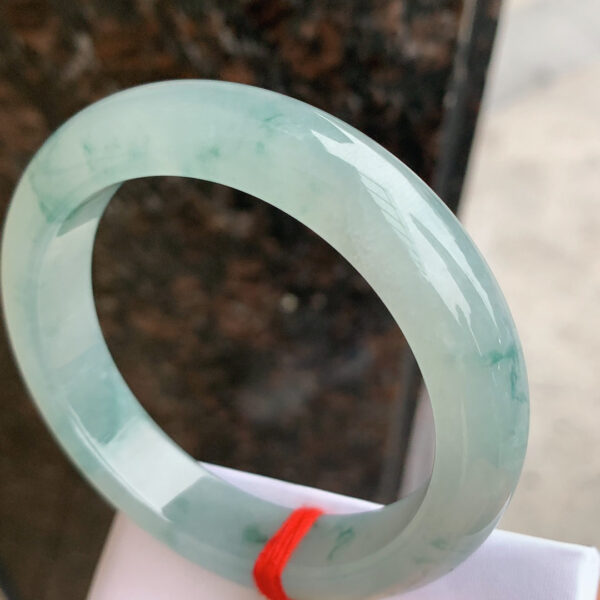 Close-up of floating floral inclusions in icy green jade bangle