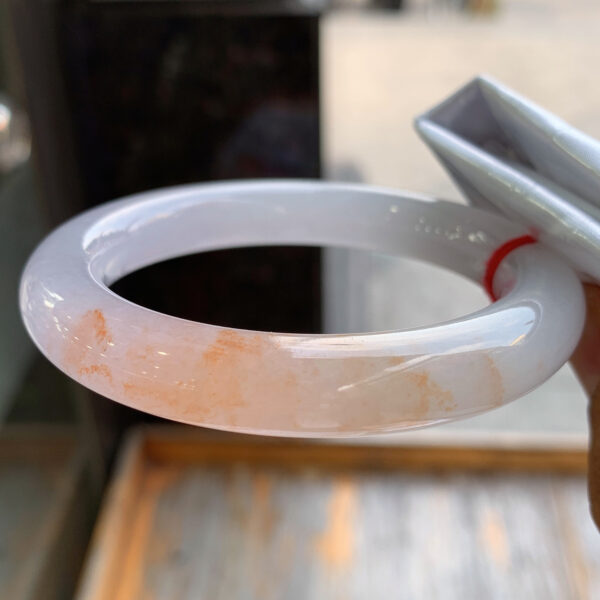 Close-up of red jadeite bangle showing translucent icy texture and 11mm thickness