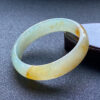 Left side view of yellow jade princess bangle with floral patterns