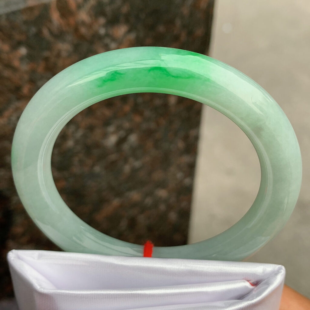 Chinese jade bracelet with intricate carvings on some jade beads, combining artistry and tradition