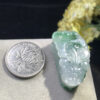Close-up of Pixiu carving on icy jade pendant emphasizing facial features