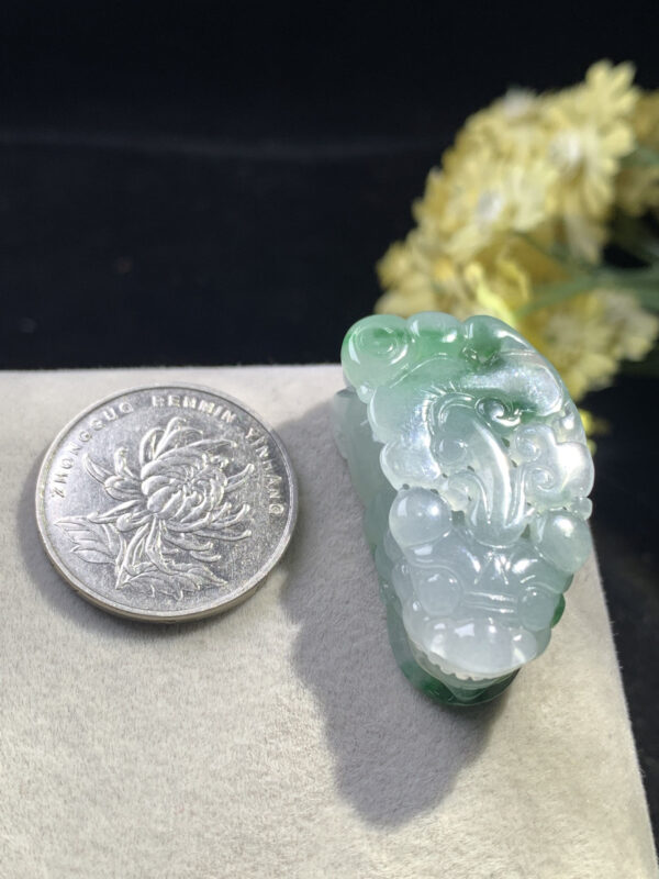 Close-up of Pixiu carving on icy jade pendant emphasizing facial features