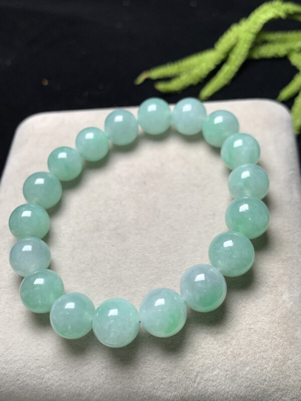 Close-up of jade mens bracelet featuring 11mm light green jadeite beads with smooth polished surface