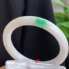 Natural jadeite bangle with white base and vibrant green stripes, oval shape 54.5mm, showcasing fine grain texture and radiant color