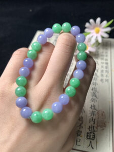 Real jade bead bracelet worn on wrist, showing elegant mix of green and lavender beads